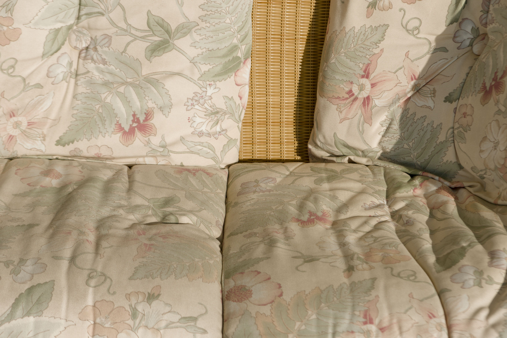 A color photo of a wicker couch with flower-painted cushions