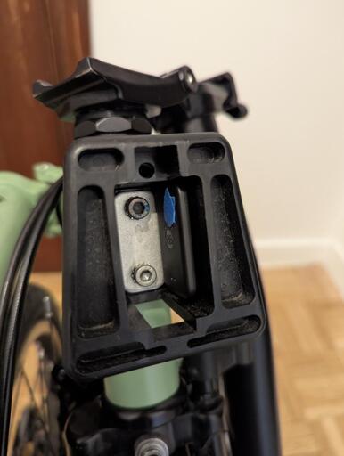 A Pebblebee Tag tracker stuck inside a disassembled Brompton Front Carrier Block