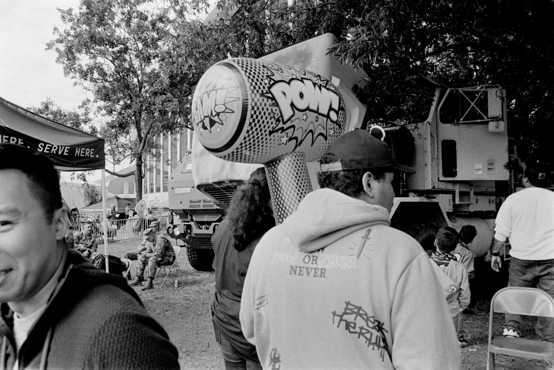 A black and white photo of a crowd at the state fair. In the center, a man holds a big inflatable hammer with the word, "POW!" on the side.

Taken on a Nikon N70 with a 28mm lens. Cinestill BWXX film. Developed at home in Ilfosol 3.