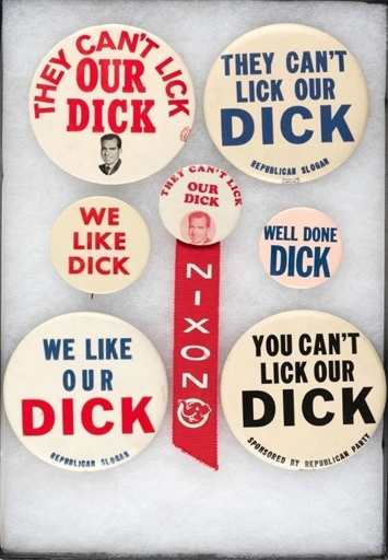 An assortment of badges and pins that say “can’t beat/lick our dick”