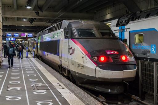 TGV Atlantique at Gare Montparnasse. Security gates are seen slightly deeper into the platform and a Île-de-France Mobilités RER train is seen behind it